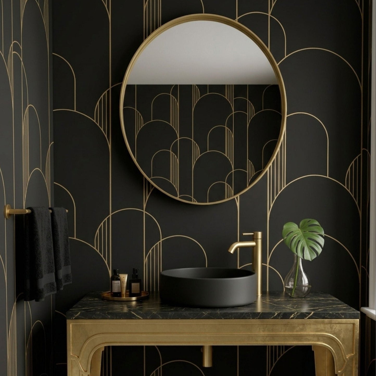 A luxury bathroom vanity setup featuring a gold-framed oval mirror, a black vessel sink, and a matching gold console table against a black wallpaper with gold geometric arch patterns.