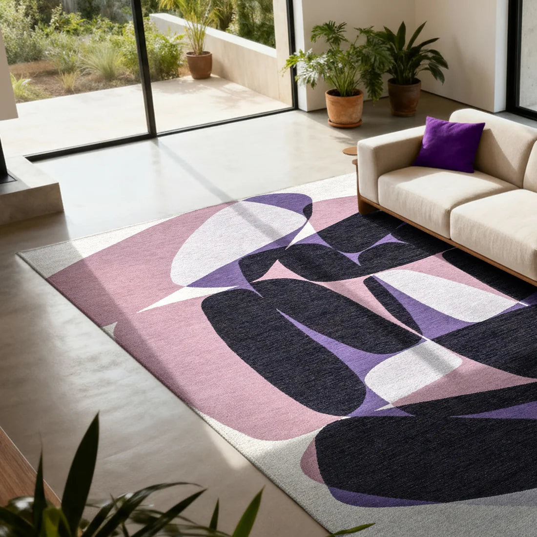 abstract rug with organic shapes in lilac, purple and pink on a white floor with a cream linen couch and violet cushion near patio doors with a garden scene