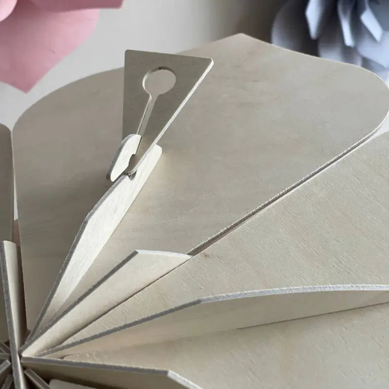 Close-up of a beige paper flower with a metal clip on a light background