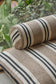 Striped fabric roll on a striped fabric surface with greenery in the background