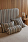Striped pillows on a bed with a wooden headboard and side table in the background