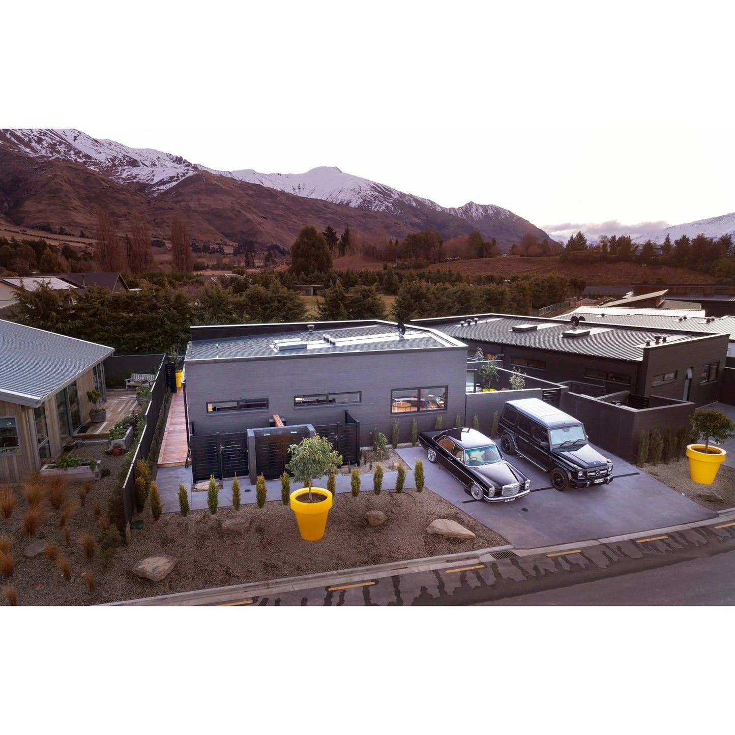 Modern building with cars parked in a driveway, mountains in the background