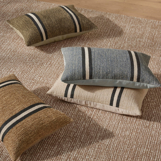 Three striped pillows on a textured rug with a wooden floor.