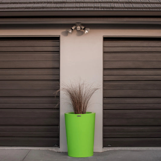 Green planter with dried plants in front of a brown garage door