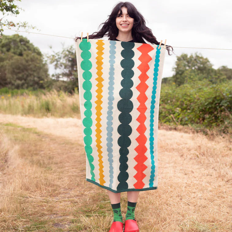 Woman holding a colorful patterned dress in an outdoor setting