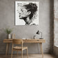 simple wooden desk and chair with a concrete wall behind featuring a large monochrome image of a womans face covered in graffiti