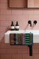 Bathroom sink with bottles and a colorful towel on a pink tiled wall.