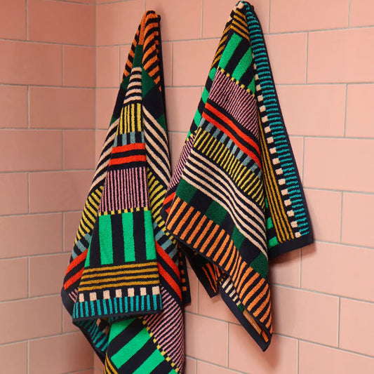 Colorful patterned towels  draped over a pink tiled wall