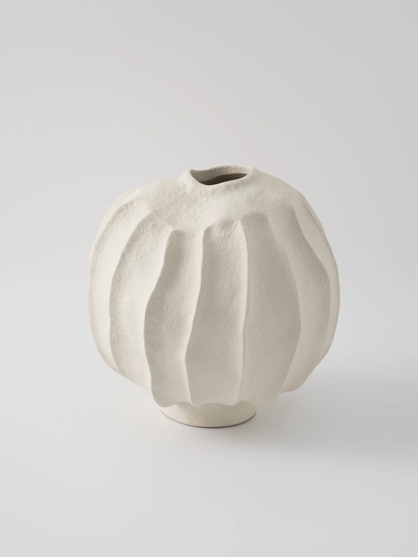 Beige ceramic vase with textured surface on a light gray background