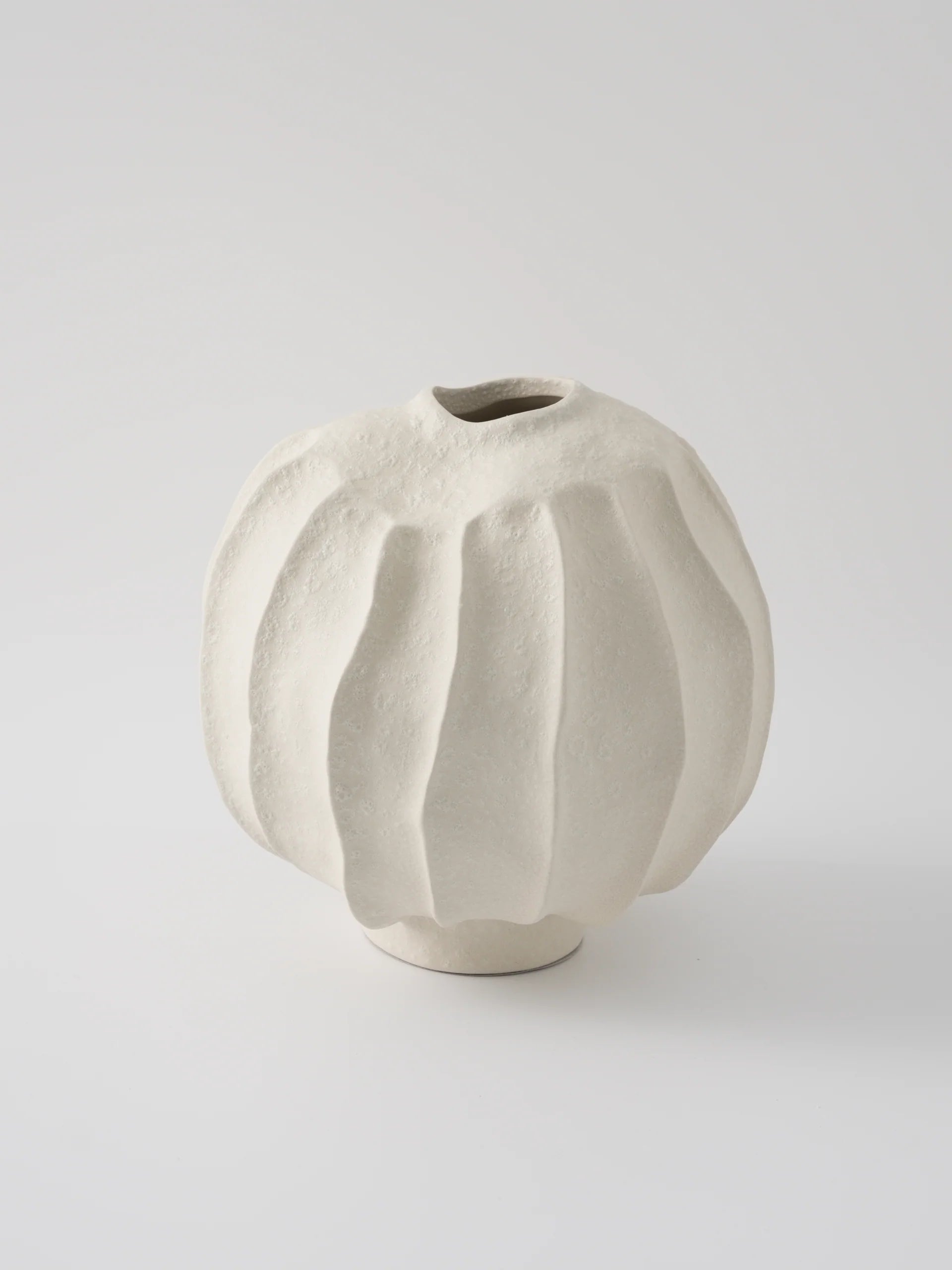Beige ceramic vase with textured surface on a light gray background