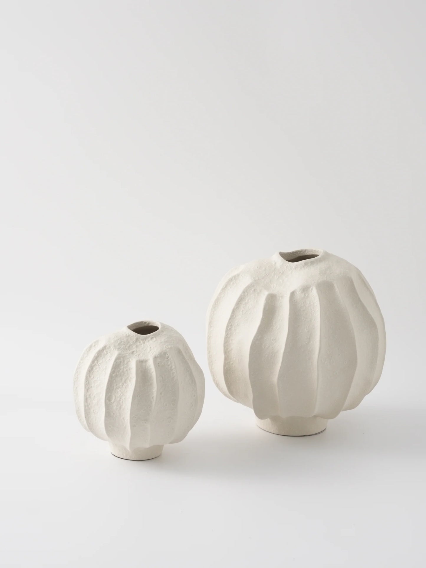 Two white ceramic vases with textured surfaces on a light gray background