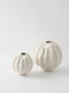 Two white ceramic vases with textured surfaces on a light gray background