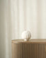 White ceramic vase on a wooden side table against a beige wall