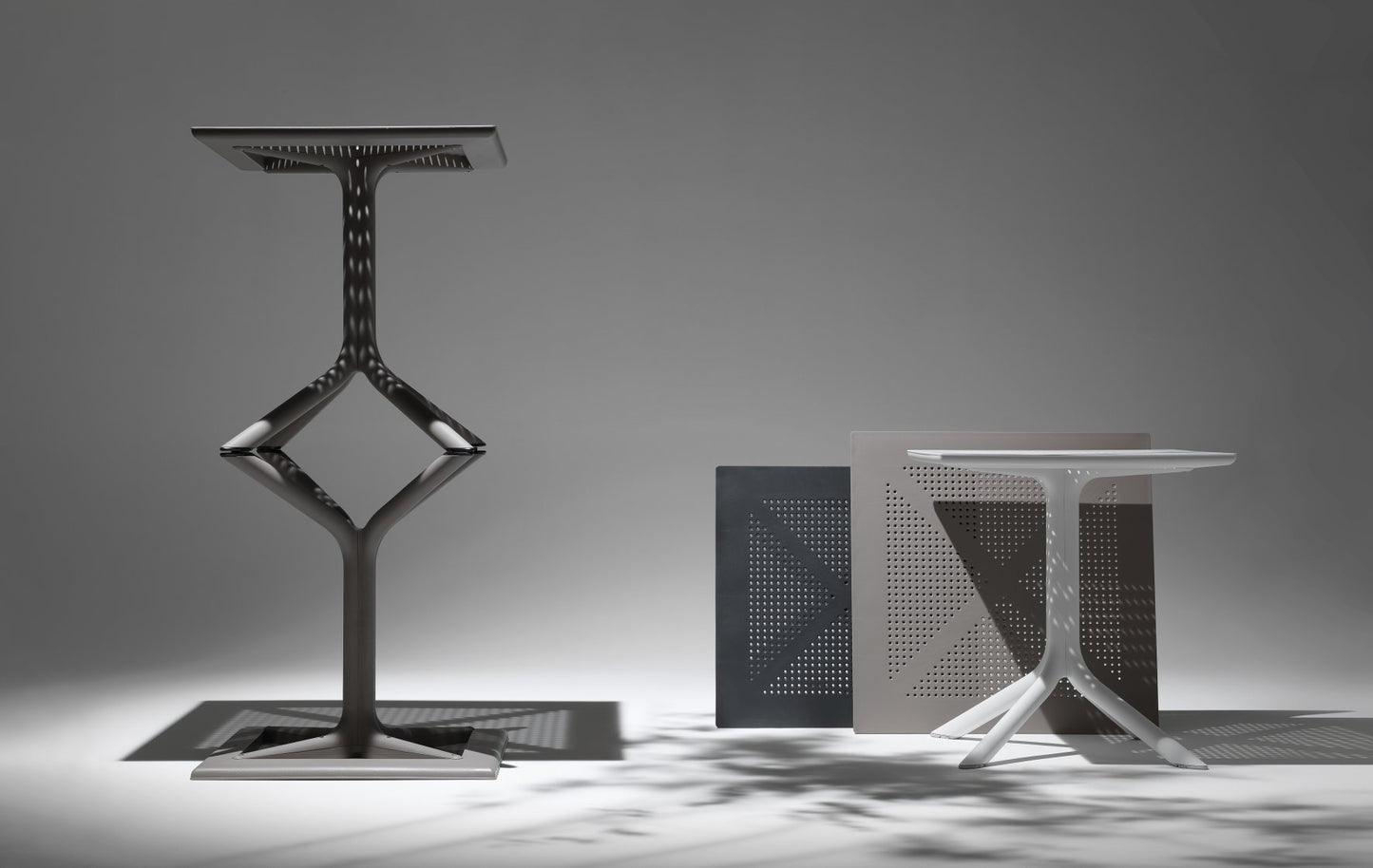 Three modern metal tables with geometric designs on a gray background