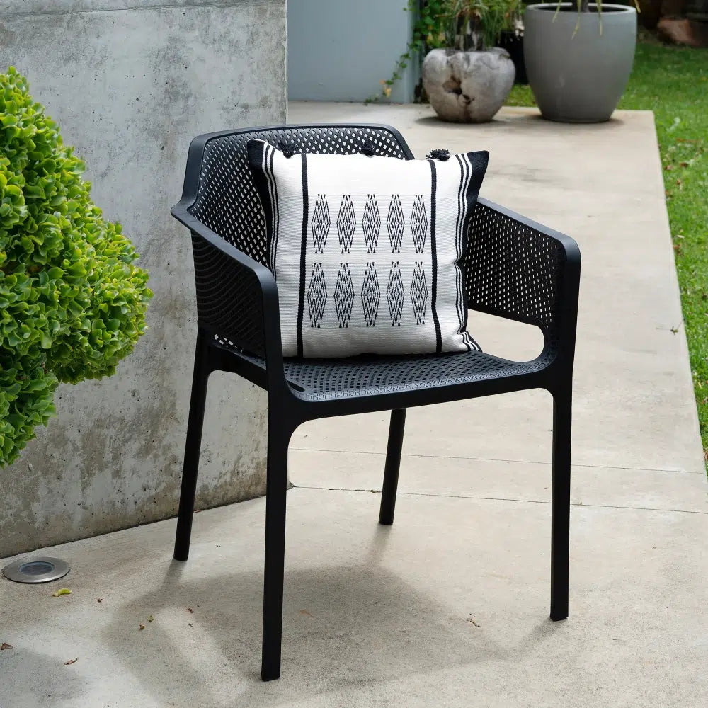 Black outdoor chair with a patterned cushion on a concrete patio.