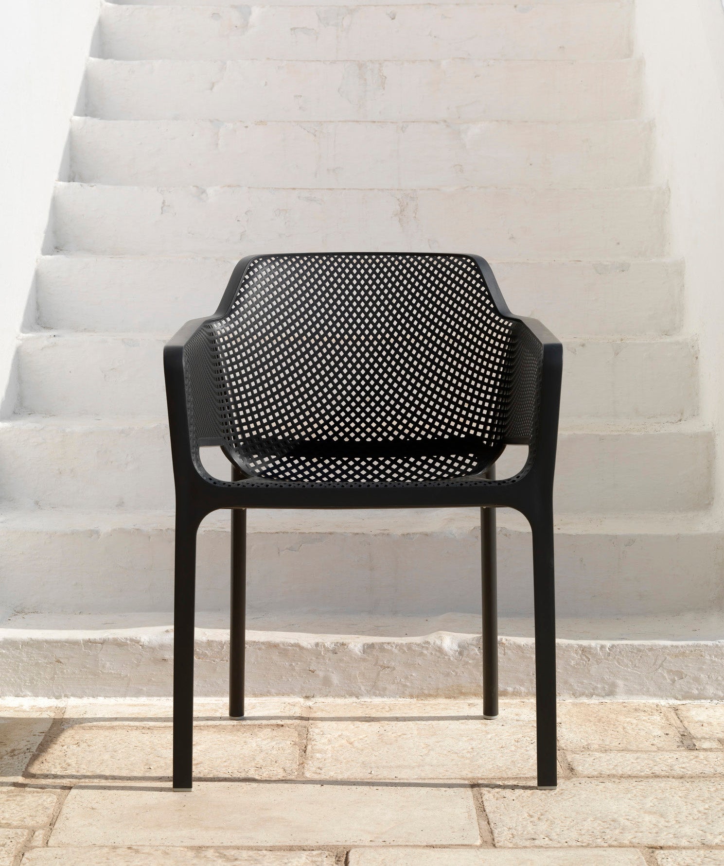 Black perforated chair on a stone staircase