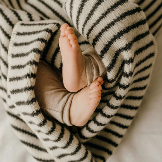Baby feet peeking out from under a striped blanket