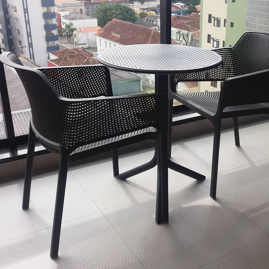 Black nardi 
table and chairs on a balcony with cityscape view
