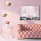 Pink living room with a tufted sofa, side table with flowers, and abstract art on the wall.