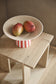 Bowl with mangoes on a wooden stool against a neutral background