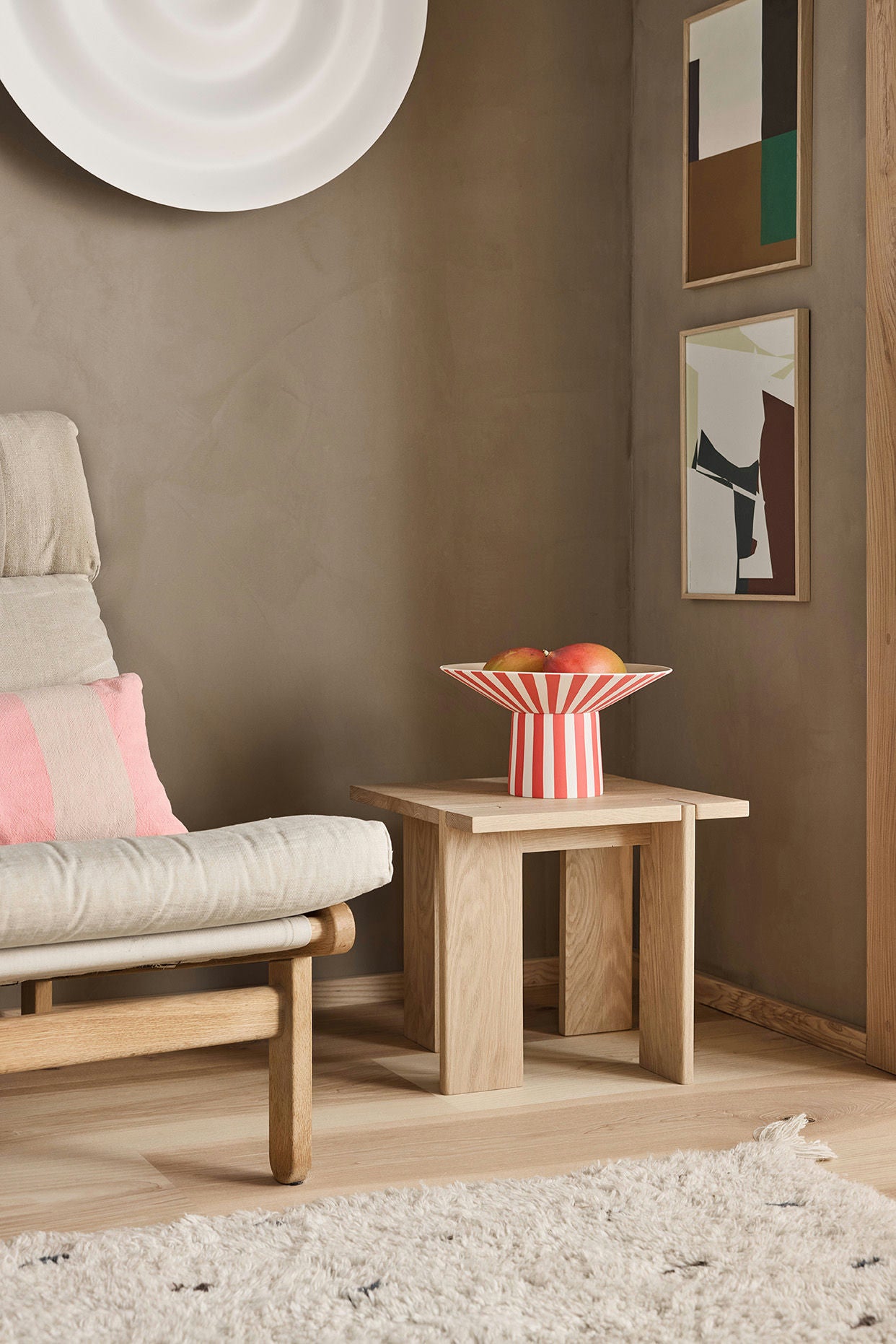 Modern living room with a beige armchair, wooden side table, and abstract art on the wall.