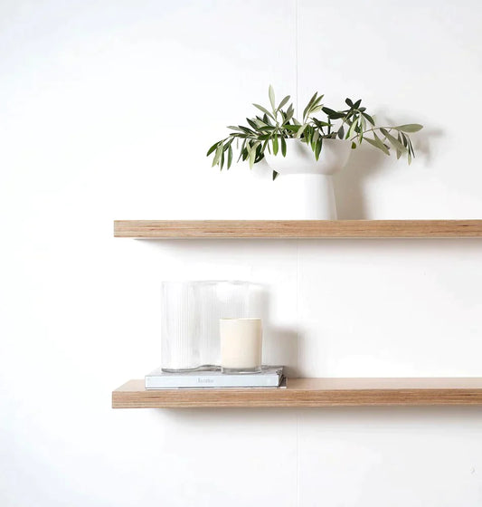 Two oak floating shelfs wiht a plant and candle on against a white background