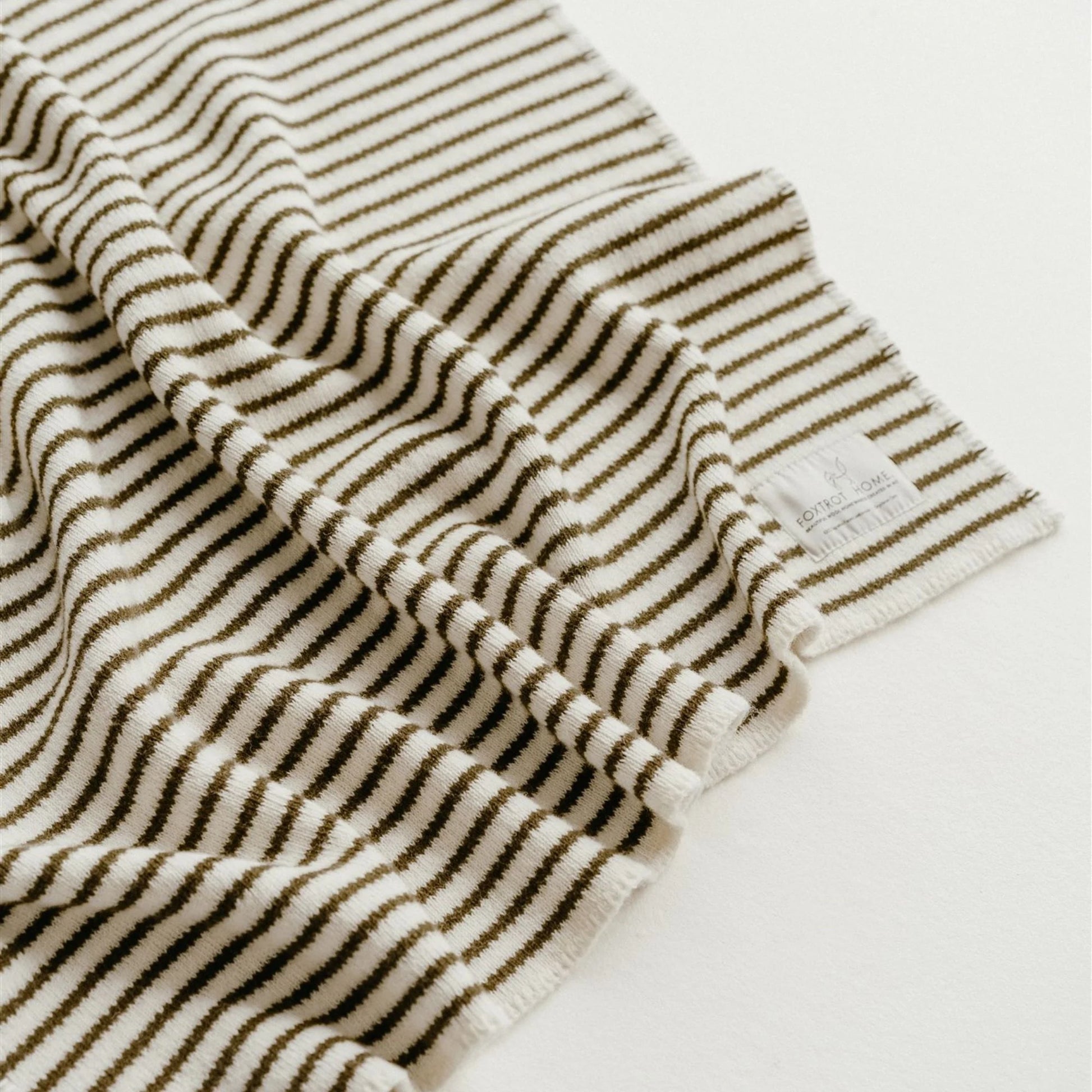 Close-up of a striped towel with a visible brand label on a white background