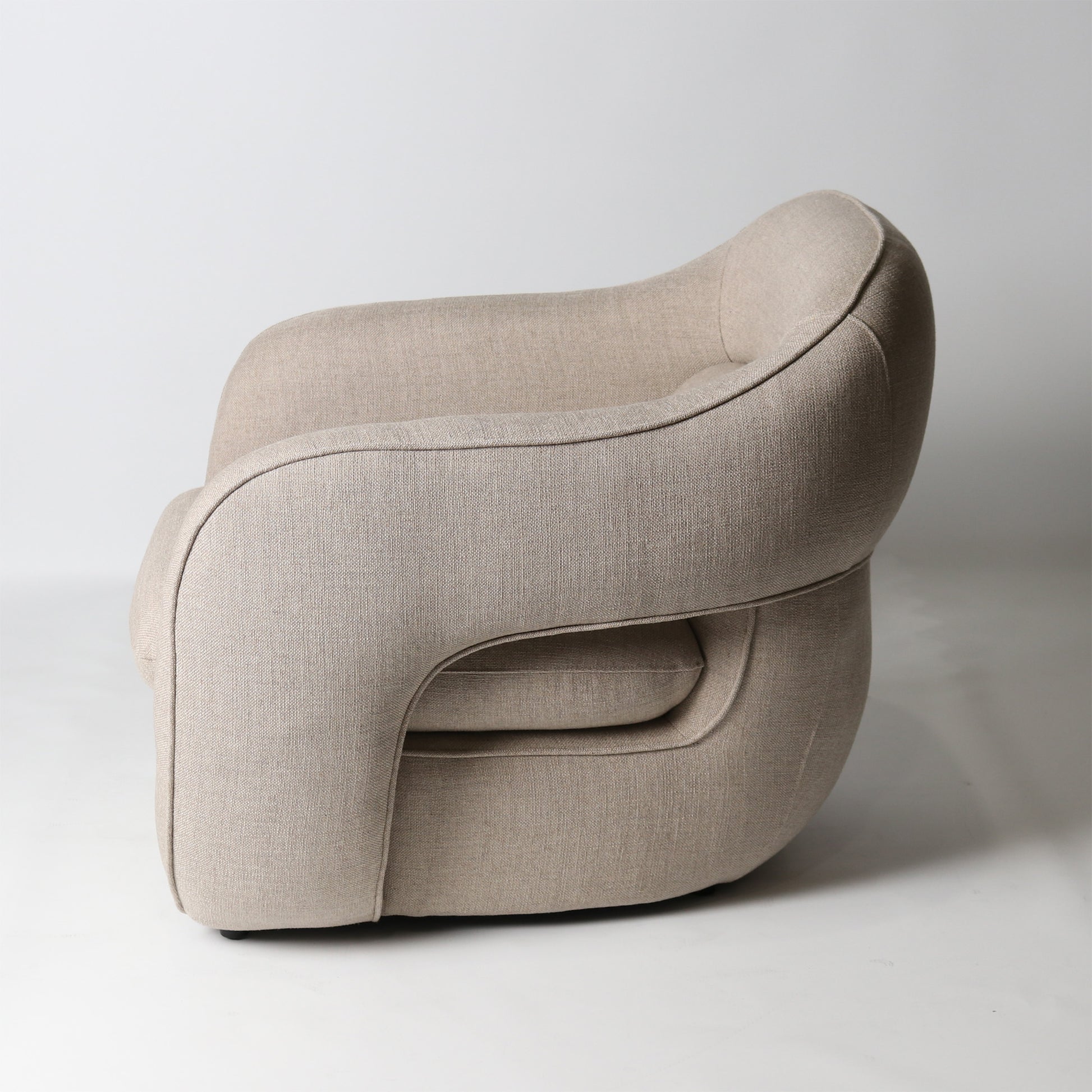 Architectural rounded open sided lounge chair in neutral fabric