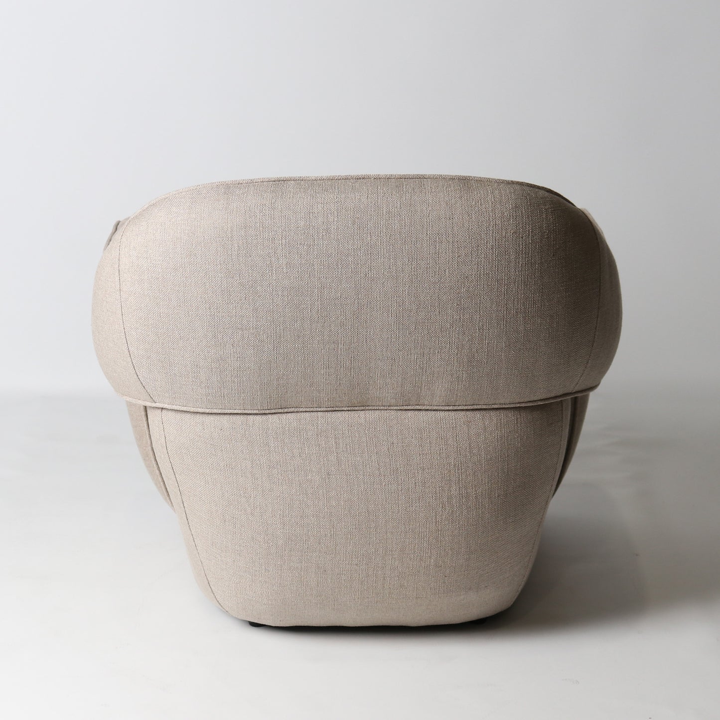 Architectural rounded open sided lounge chair in neutral fabric - back view