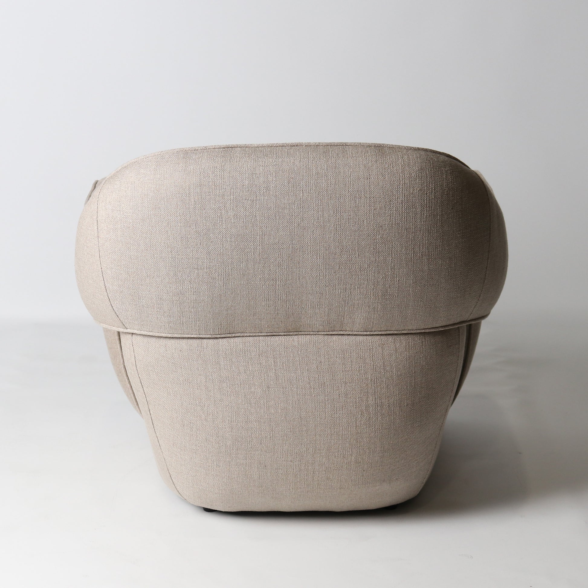 Architectural rounded open sided lounge chair in neutral fabric - back view