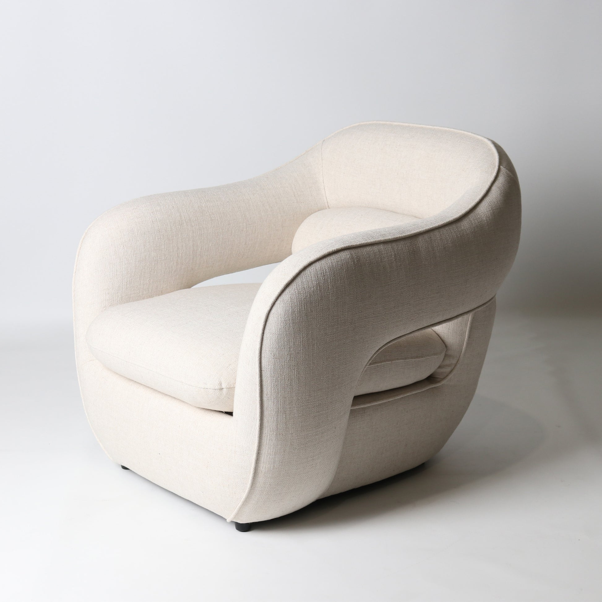 Architectural rounded open sided lounge chair in neutral fabric