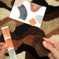 Person holding color swatches against a textured brown surface