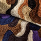 Close-up of a textured rug with wavy pattern in brown, blue, and beige.