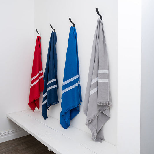 Four colorful towels hanging on hooks against a white wall.
