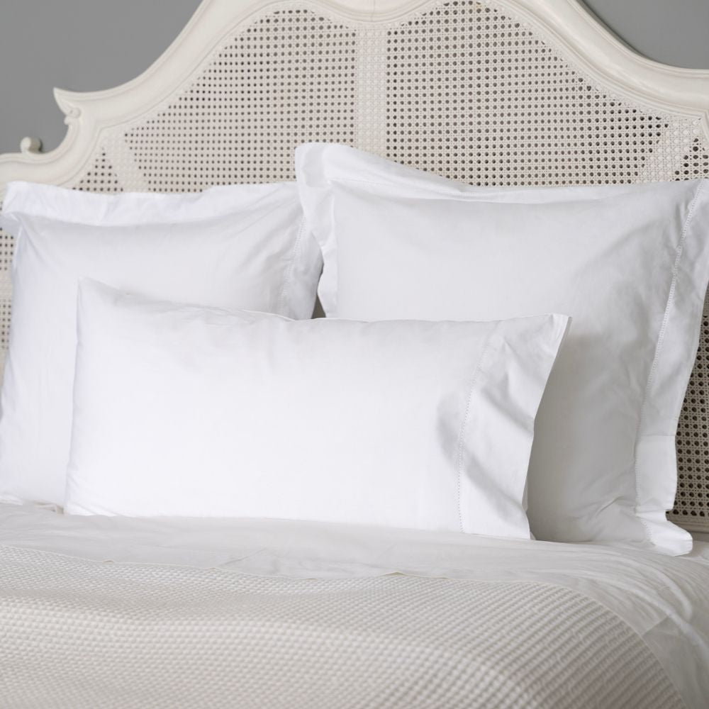 White pillows on a bed with a textured headboard