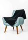 A light blue upholstered armchair with wooden legs, draped with a dark charcoal knit throw blanket, photographed on a clean white studio background.
