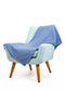 Light blue armchair with a blue blanket draped over it on a white background