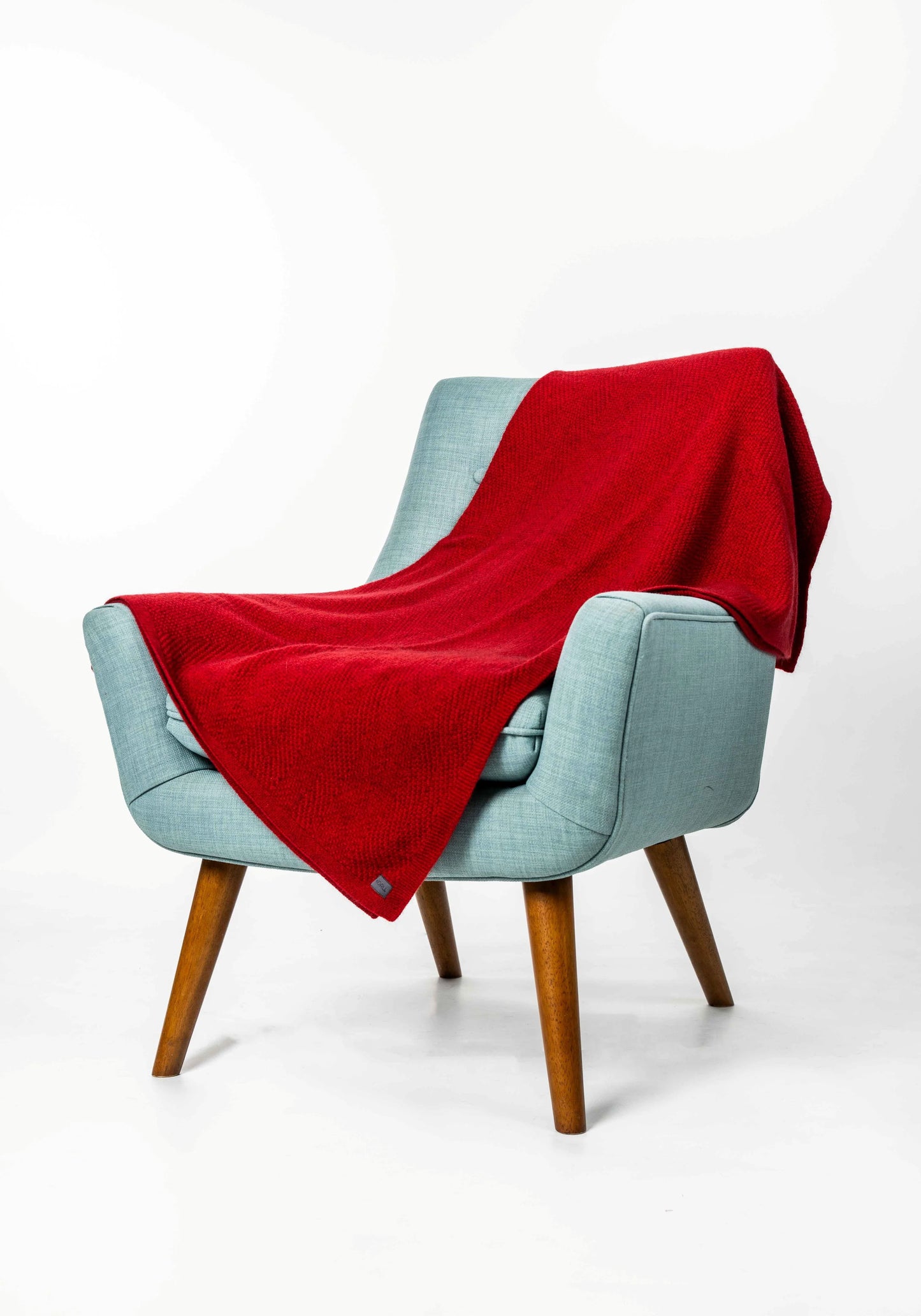 Light blue armchair with a red blanket draped over it on a white background