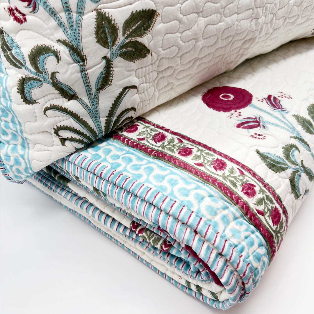 Stack of floral and striped patterned quilts on a white surface