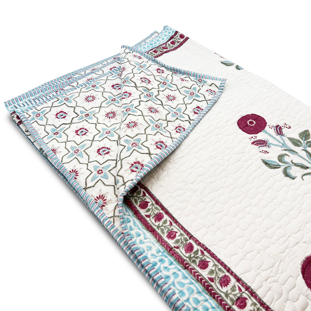 Floral patterned quilt with a folded corner on a white background