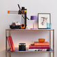 Metal shelf with a 3D printer, books, lamp, and decorative items against a light background