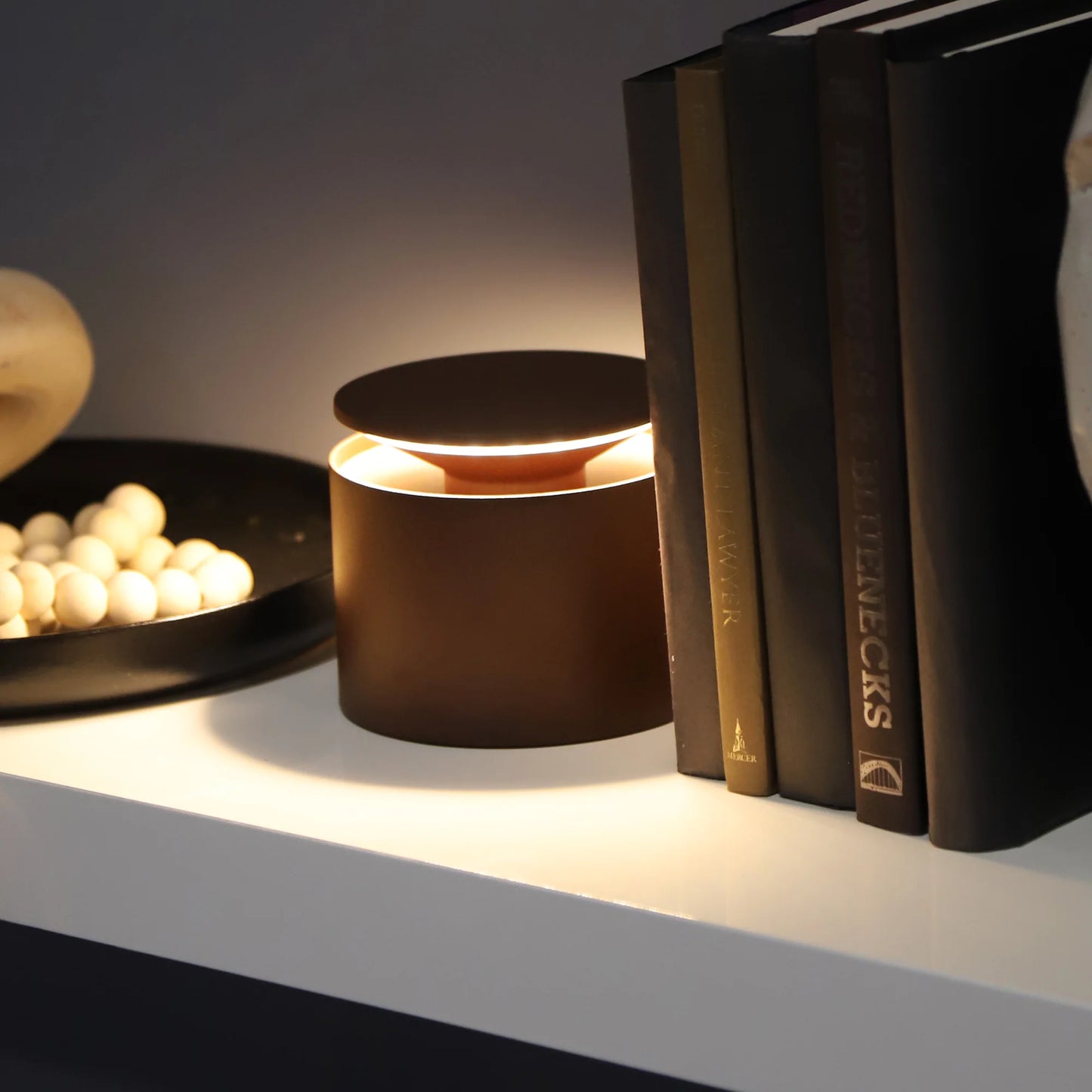 brown cylindrical  on a shelf with books and decorative items.