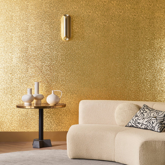 Modern living room with gold textured wall, beige sofa, and decorative table.