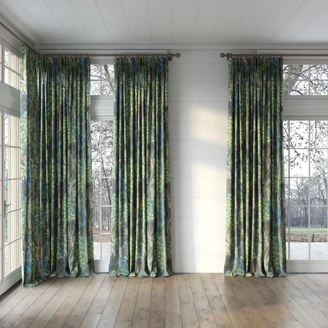 Three patterned curtains hanging in a room with large windows.