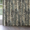 Curtains with a peacock and foliage pattern in a room with a window.