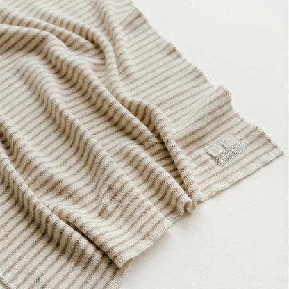 Close-up of a beige and white striped fabric with a brand label on a light background