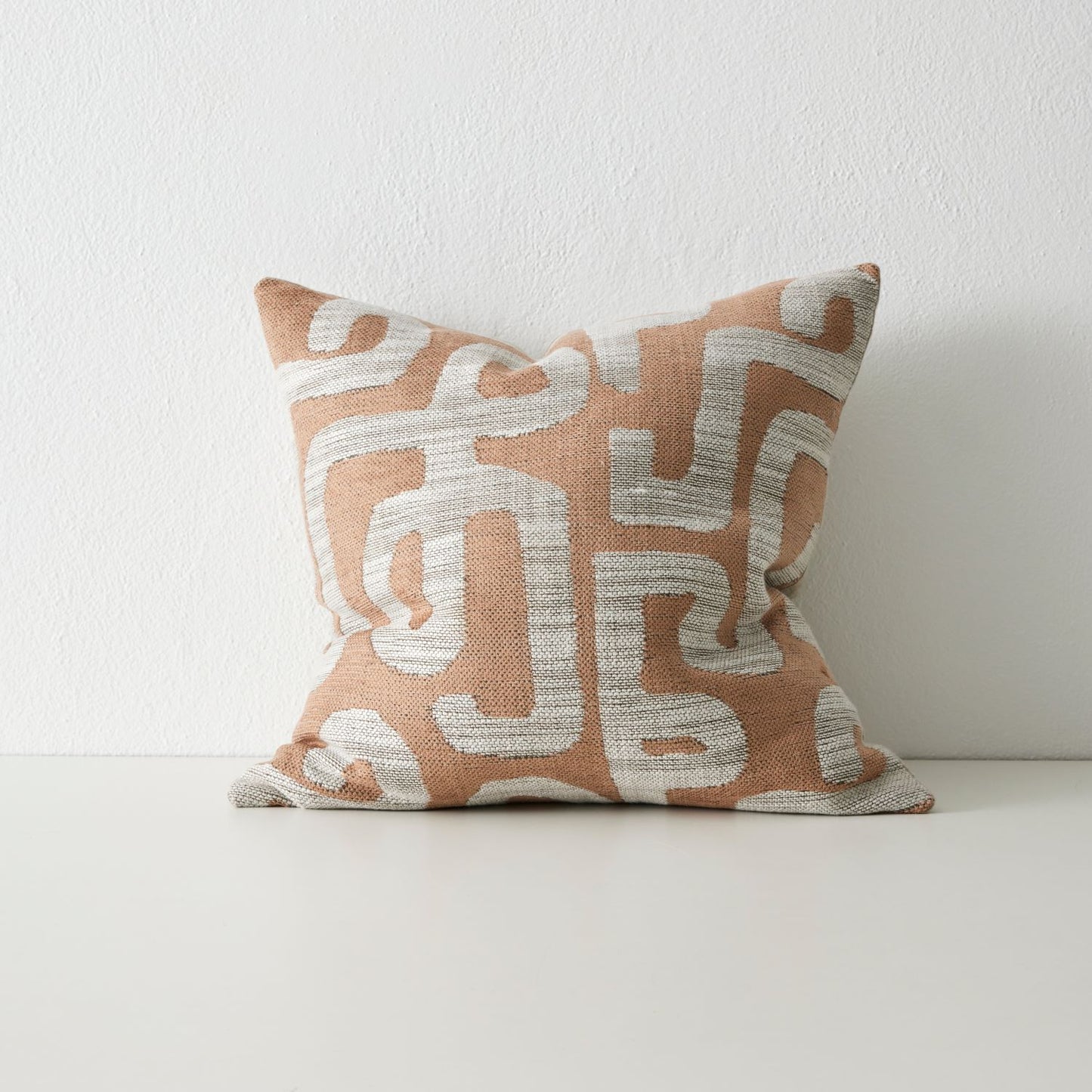 Serene cushion with geometric ikat pattern in coral and grey