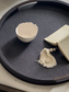 Anthracite shagreen  tray with a white bowl, beige pouch, and tassel on a light background
