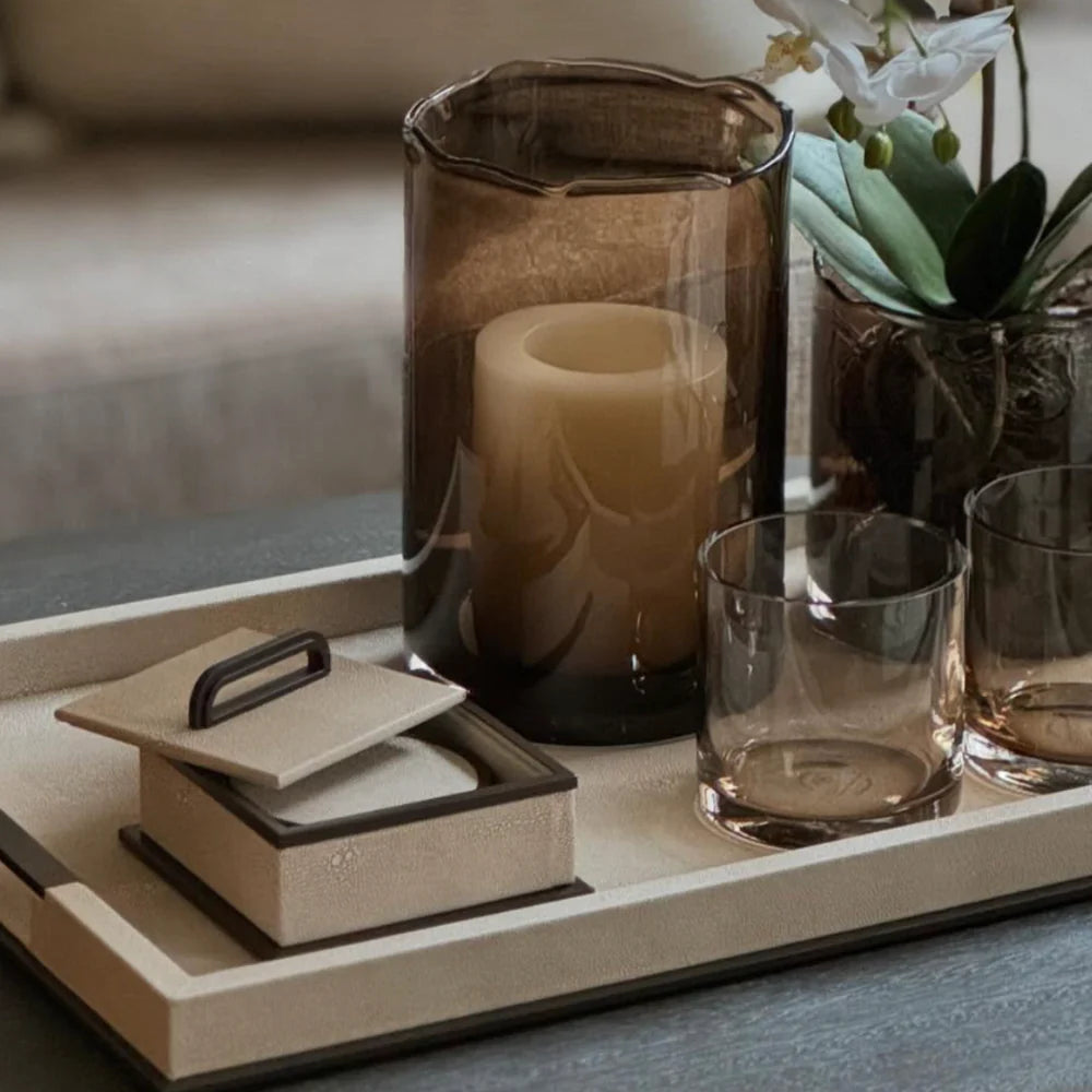 Decorative tray with candle, glass, and small book on a surface