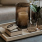 Decorative tray with candle, glass, and small book on a surface